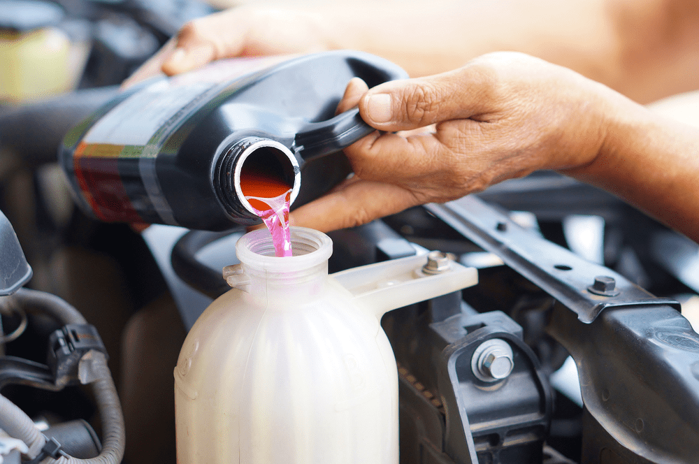 hand filling car cooling system with coolant